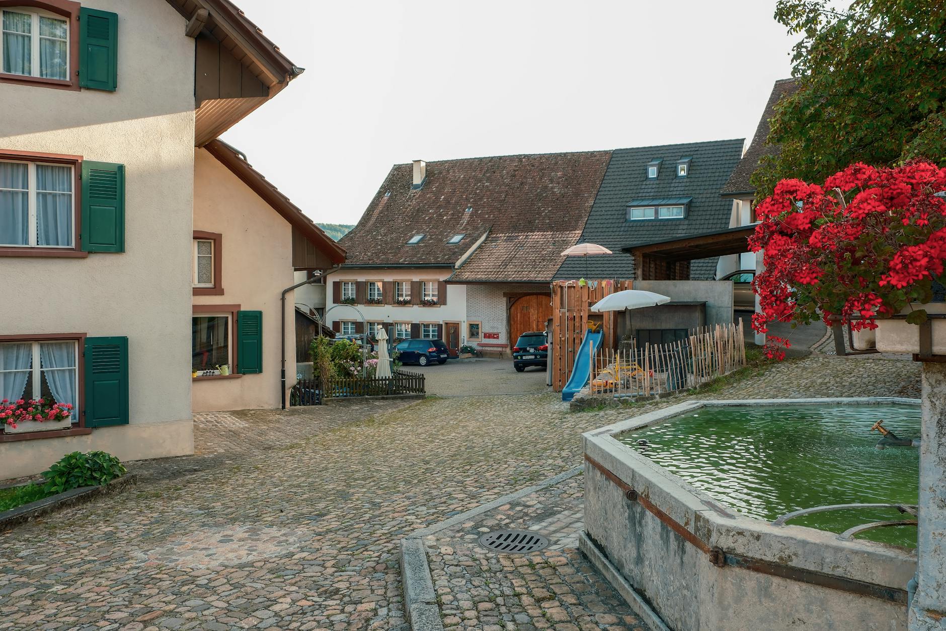 Malownicza europejska uliczka z brukiem, kamienicami i małą fontanną