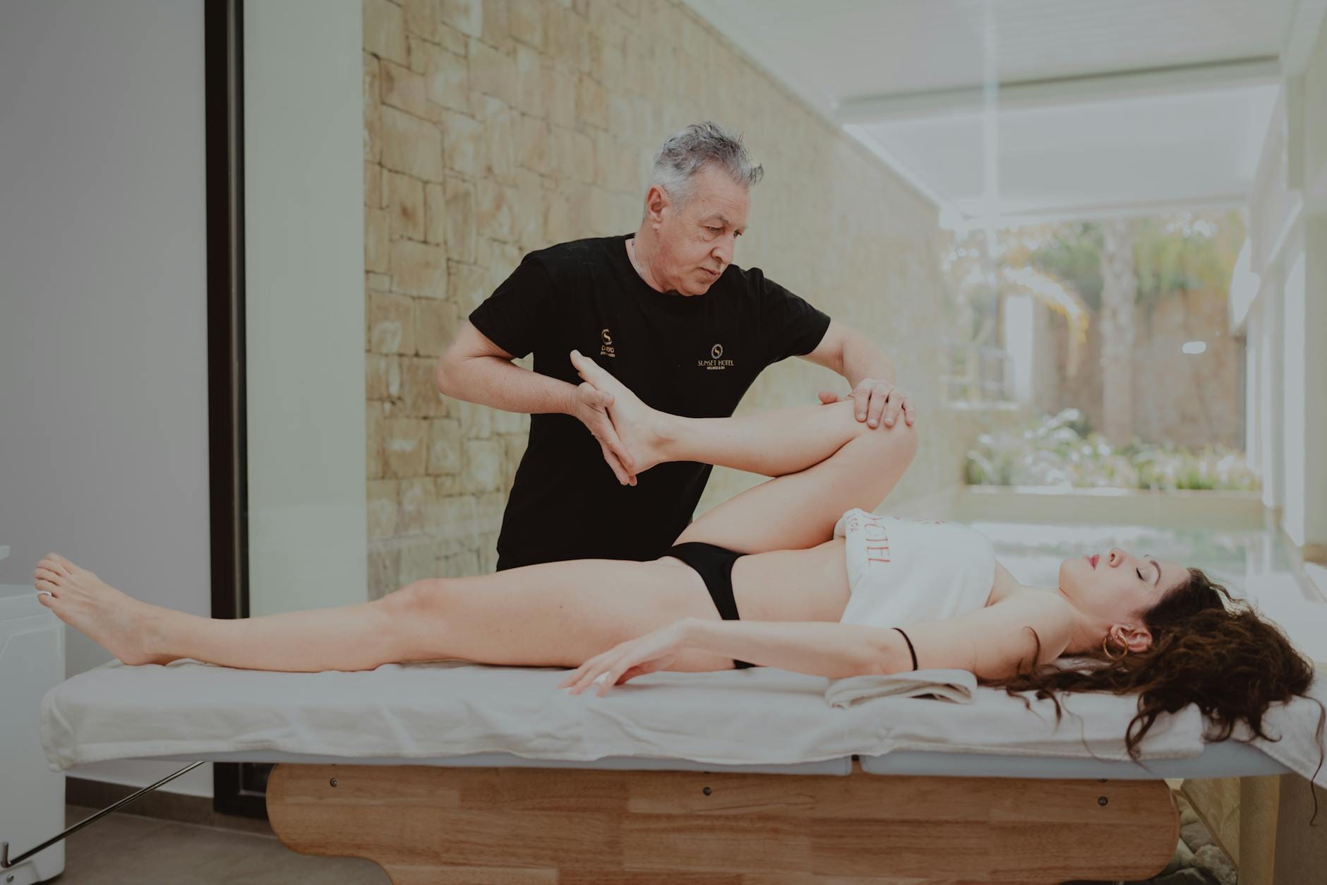 Fizjoterapeuta pomaga sportowcowi w ćwiczeniach rozciągających po treningu
