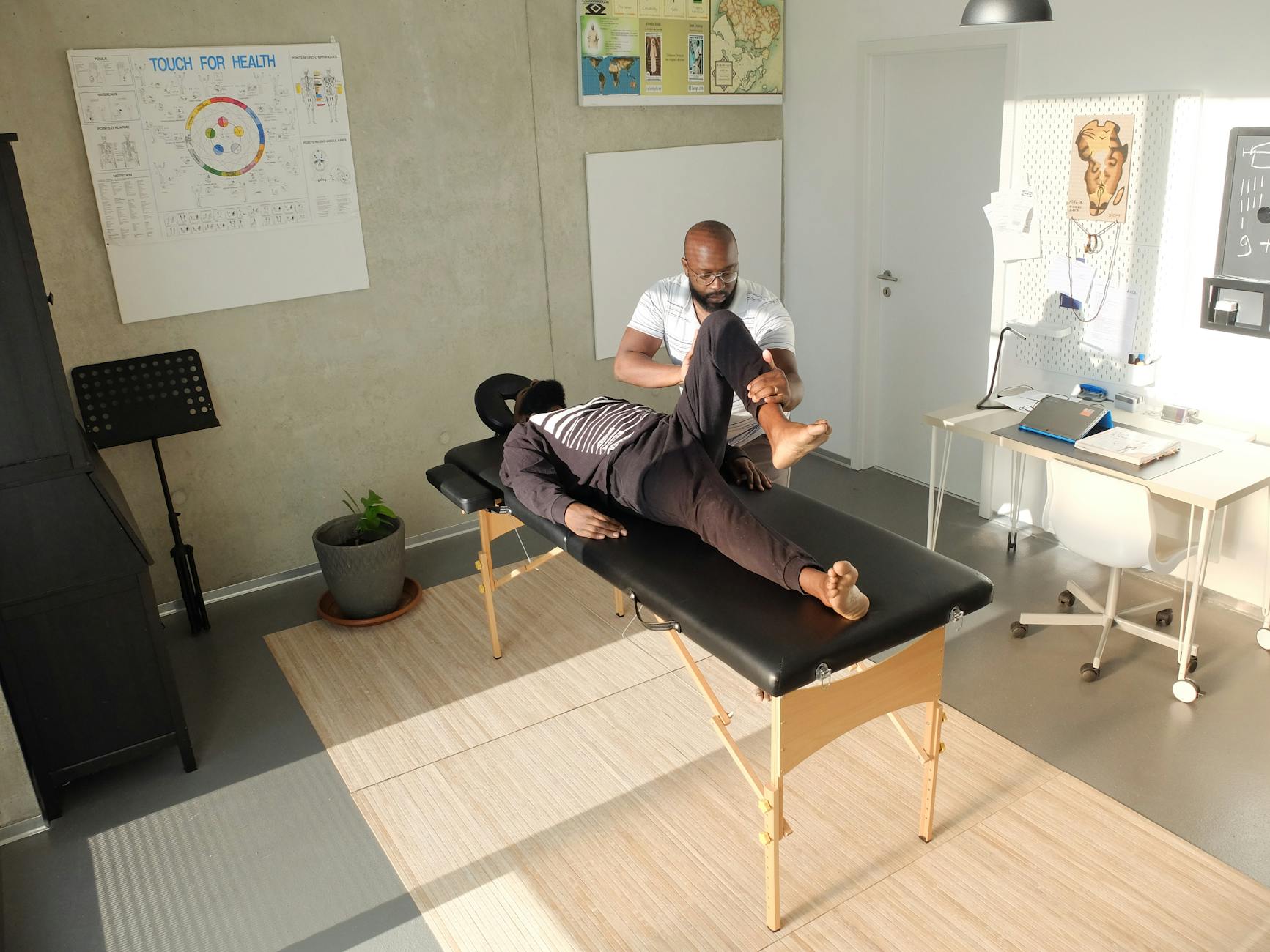 Terapeuta wykonuje masaż sportowy w gabinecie rehabilitacyjnym