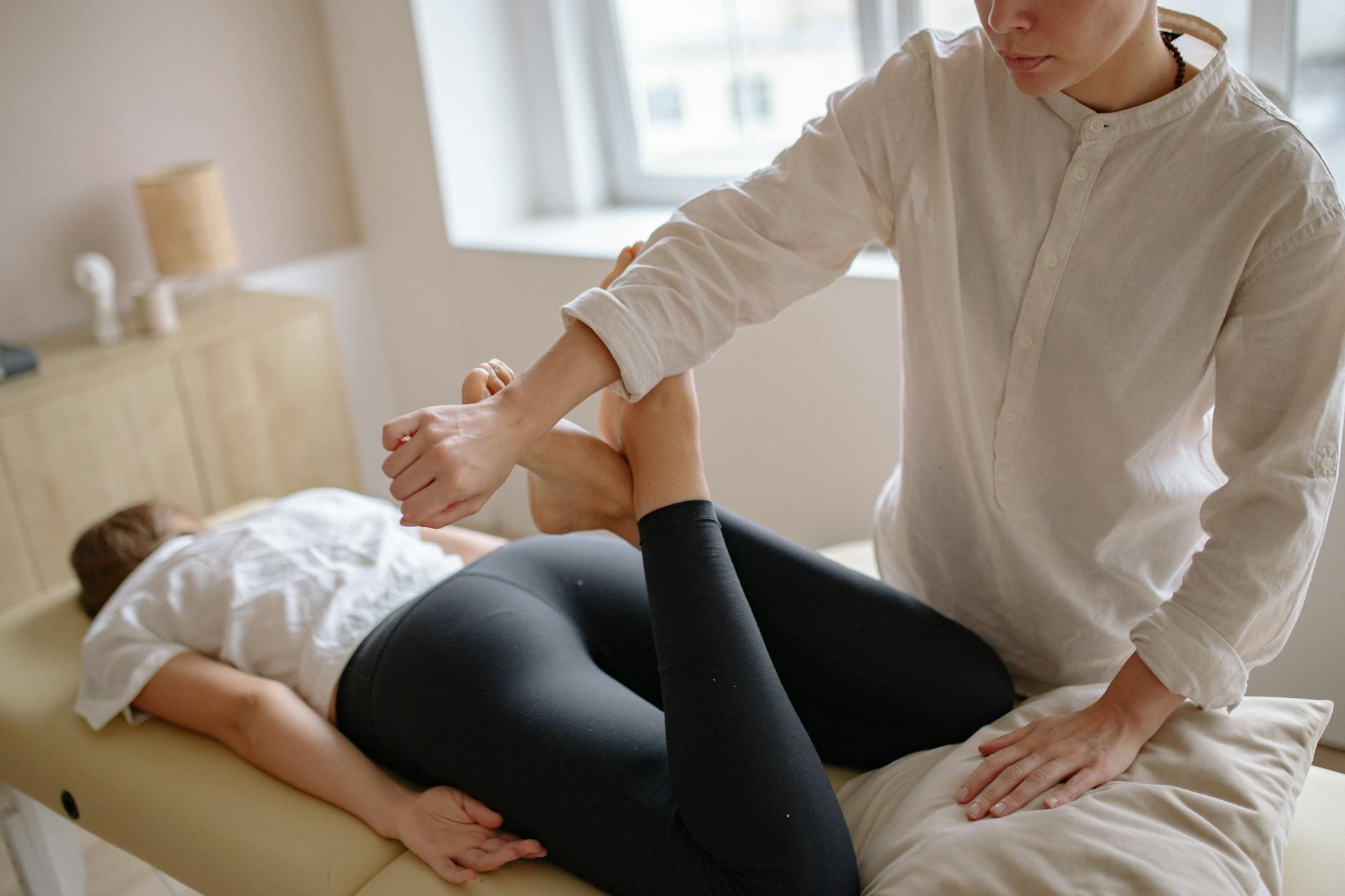 Terapeuta wykonuje zabieg drenażu limfatycznego na nodze pacjenta