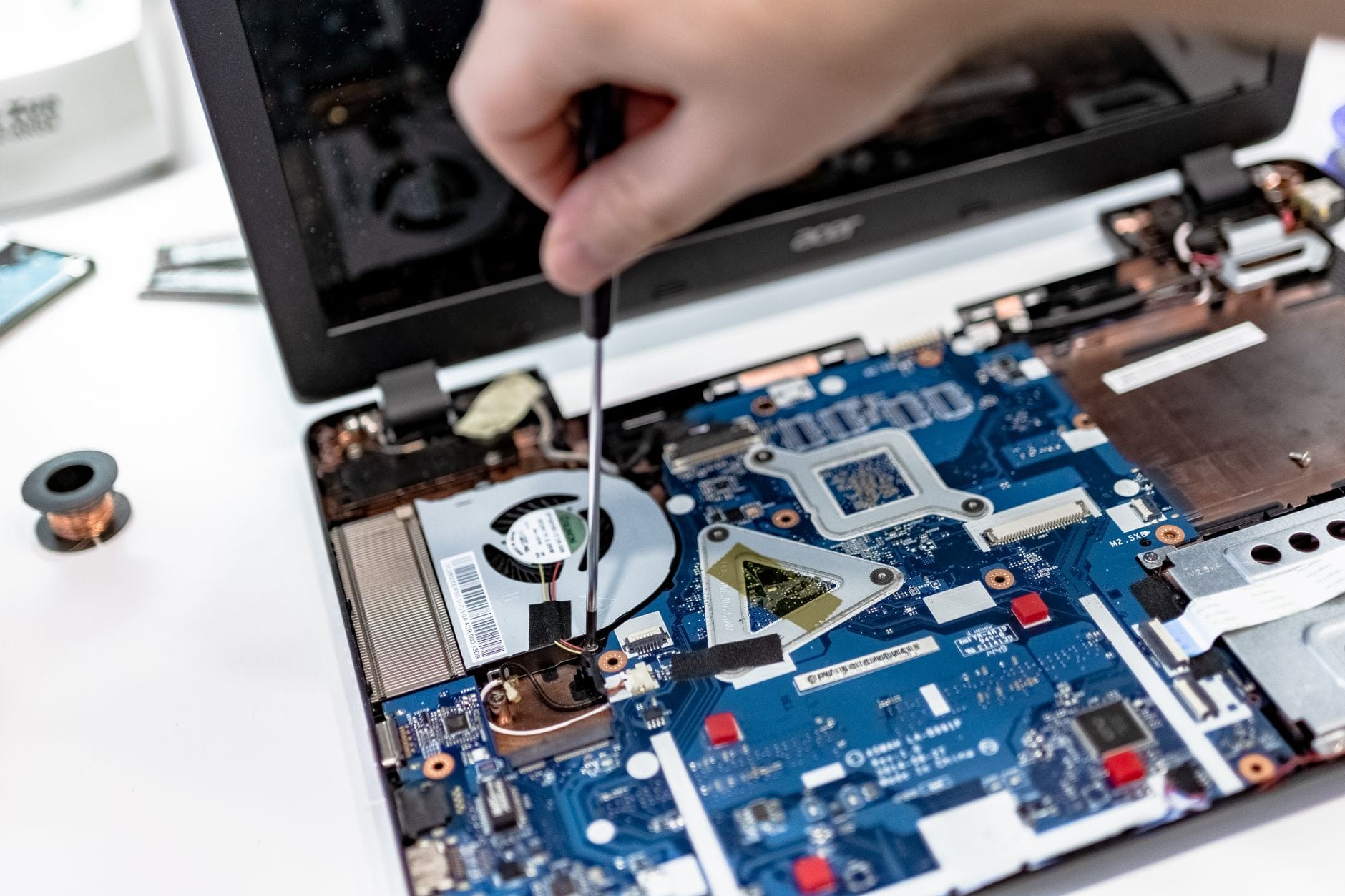 Ręka serwisanta naprawiająca płytę główną laptopa śrubokrętem