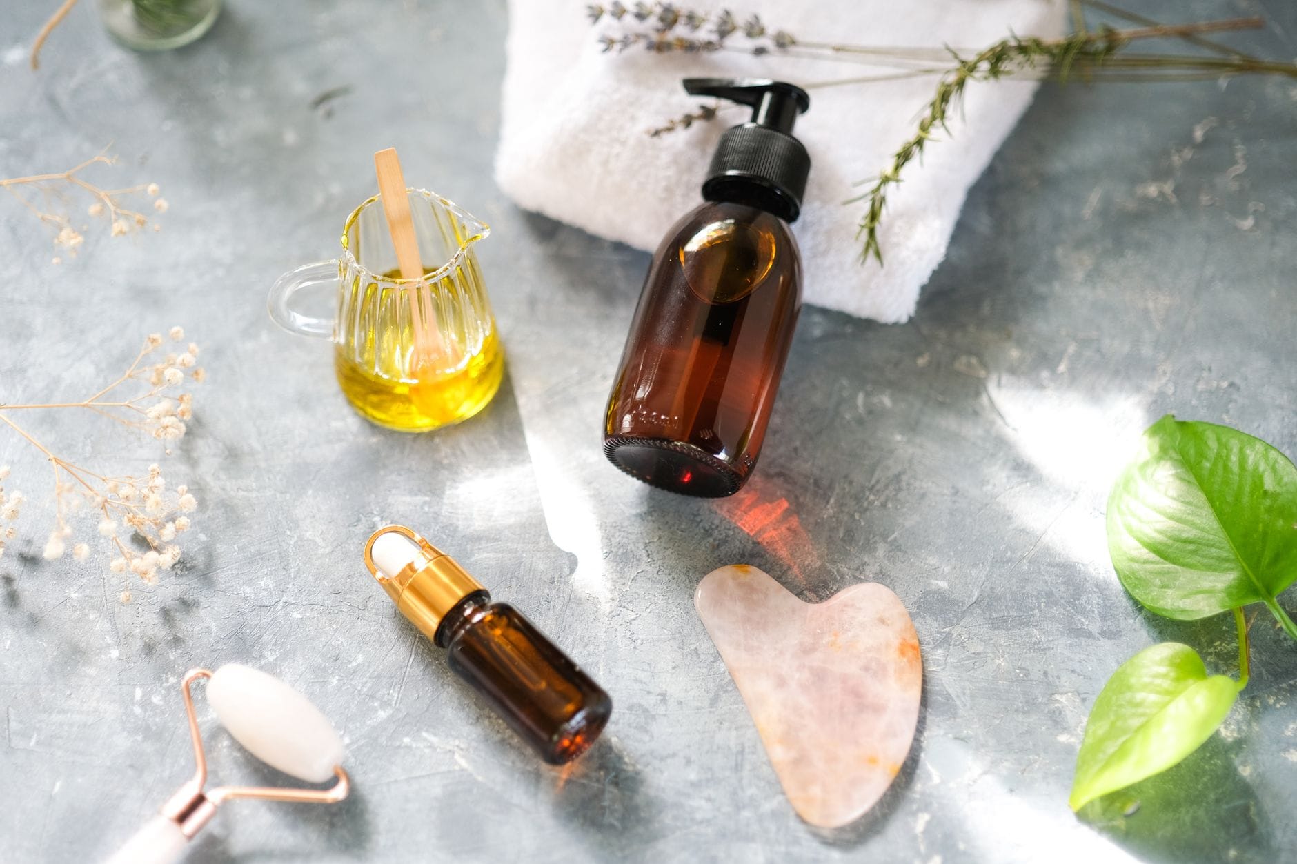 Kosmetyki i olejki do masażu kobido ułożone obok jadeitowego rollera