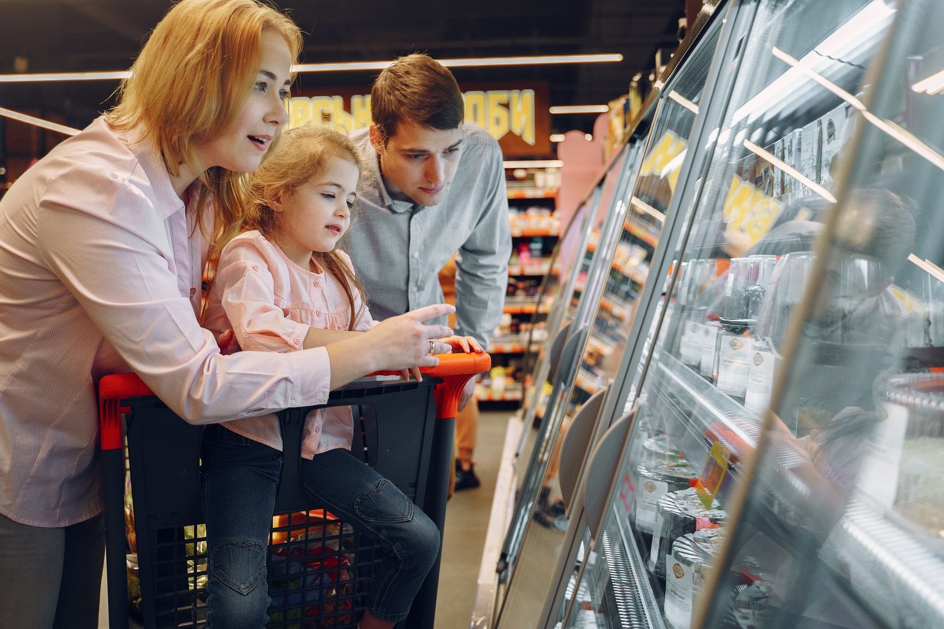 Rodzina z dziećmi robi zakupy przy lodówkach w supermarkecie
