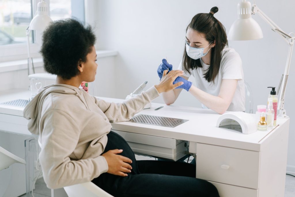 Kobieta w ciąży podczas manicure w salonie kosmetycznym